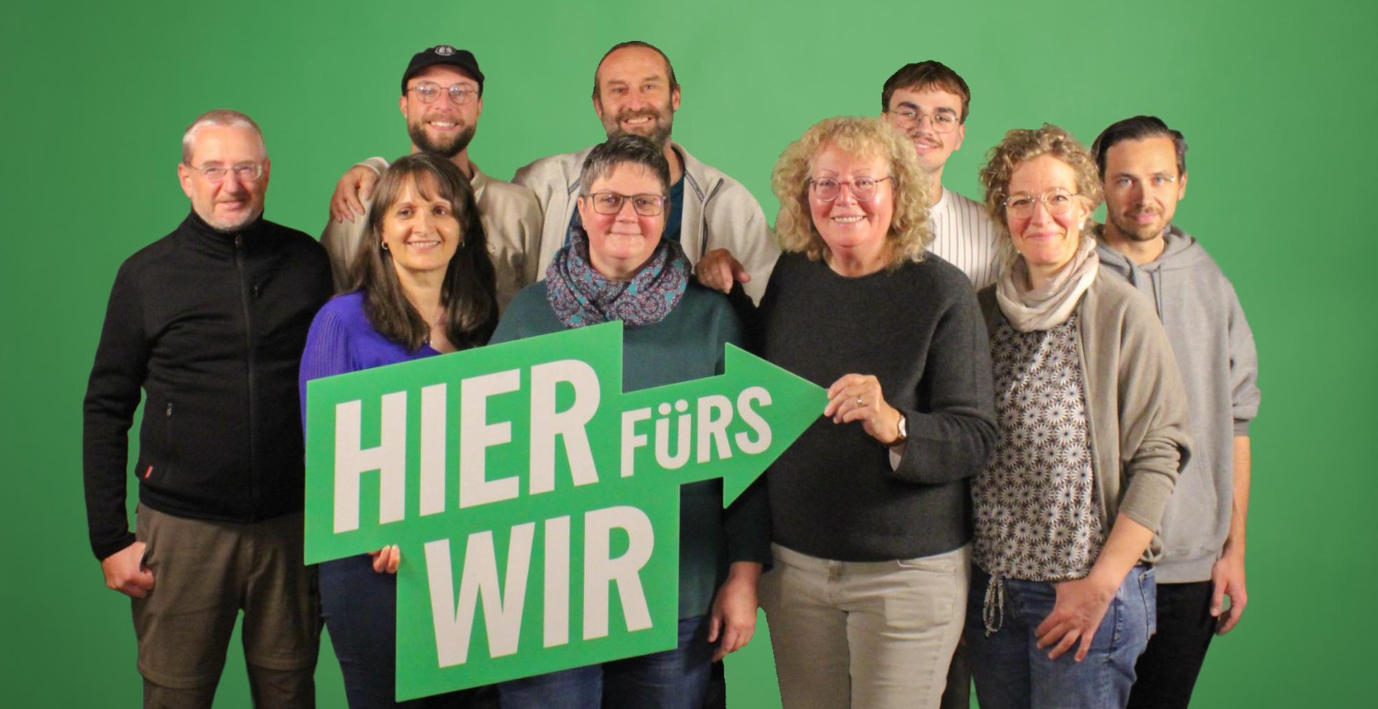 Die Kandidierenden für die Gemeinderatswahl 2026 mit einem großen Schild "Wir fürs hier"